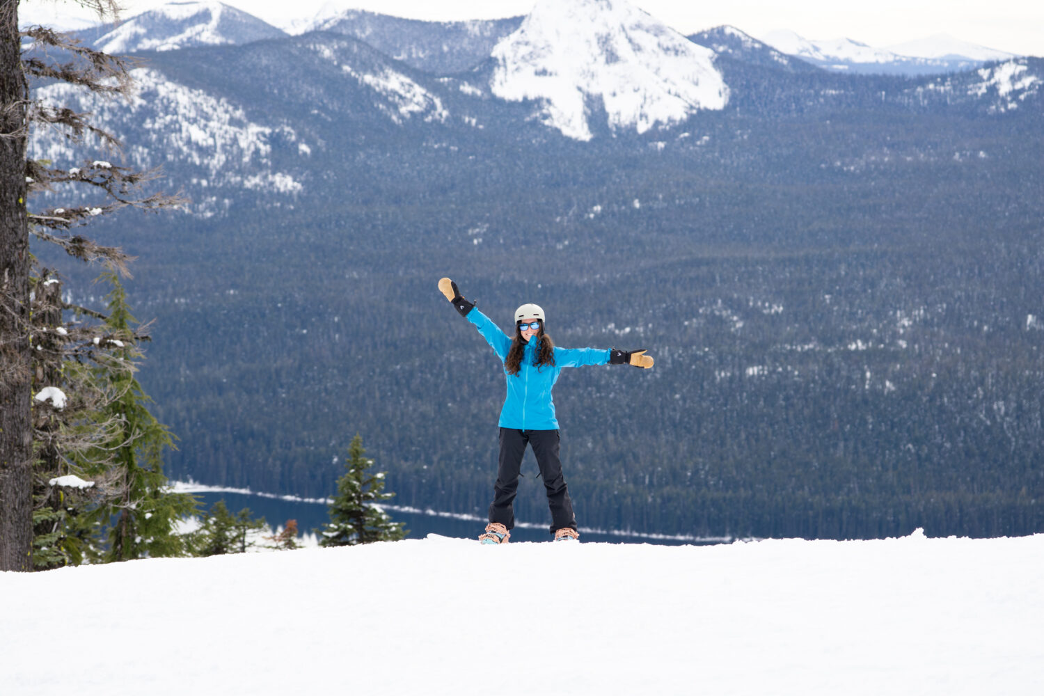 Female snowboarder at Willamette Pass Ski Resort with mountains and Odell Lake in the background